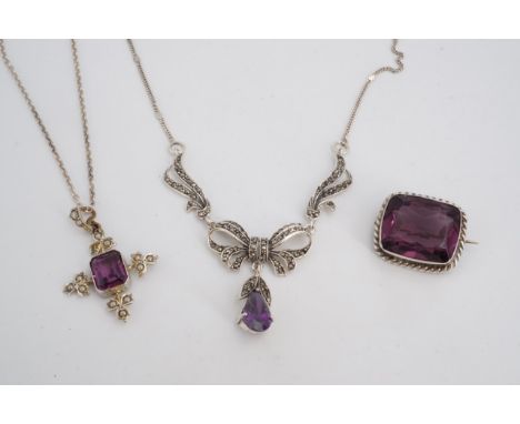 An amethyst-coloured stone and seed pearl pendant cross, a marcassite and amethyst coloured necklace and a brooch