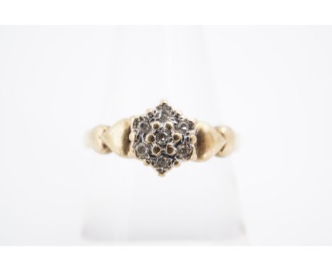 A diamond cluster ring, the small stones millegrain-set on a 9 ct gold shank, the shoulders faced with hearts, N