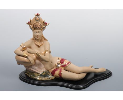 A contemporary ceramic figurine modelled as a young south Asian woman recumbent in exotic dress, 46 cm x 30 cm high