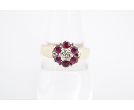 A ruby and diamond flowerhead cluster ring, the stones set of a broad tapering 9 ct gold shank, P