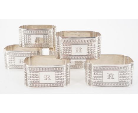 Six George V silver napkin rings, each of rectangular section with re-entrant corners and decorated with engine-turning, bear