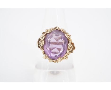 An amethyst cocktail ring, the oval stone (12 x 9 mm) on a granular setting and 9 ct gold shank, O