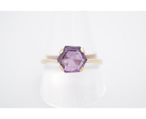 An amethyst solitaire ring, the 7 mm hexagon-cut stone set on a yellow metal shank, stamped 9 ct, T