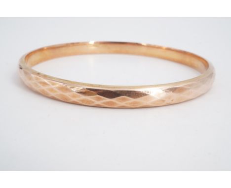 A 1930s 9 ct gold circular bangle, decorated with diamond facets overall, 7.5 cm, 8.8 g