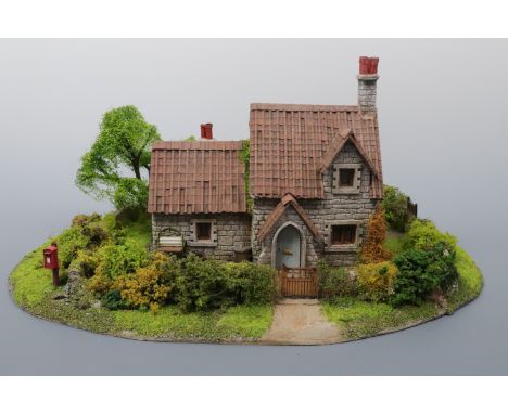 A hand-built built scale model of a two-storey Lakeland stone cottage, with enclosed garden containing a clothes wringer and 