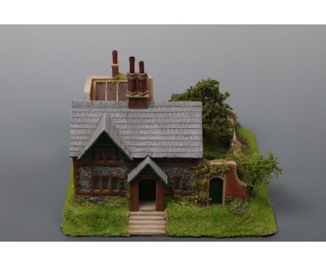 A hand-built scale model of a Victorian Lakeland two-storey pebble dashed cottage, with walled garden and orangery, 21 cm