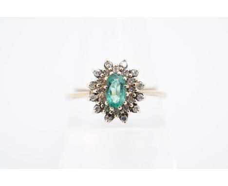 An emerald and diamond flowerhead cluster ring, the central oval-cut emerald 5 x 3 mm, having a 9 ct gold shank, Q/R