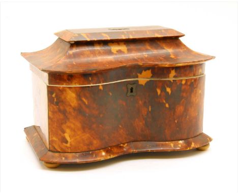 An early 19th century tortoiseshell tea caddy of serpentine outline, fitted pair of canisters on squat feet
