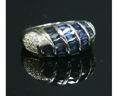 A Continental white gold, sapphire and diamond bombé ring, with diagonal rows of channel set rectangular French cut sapphires