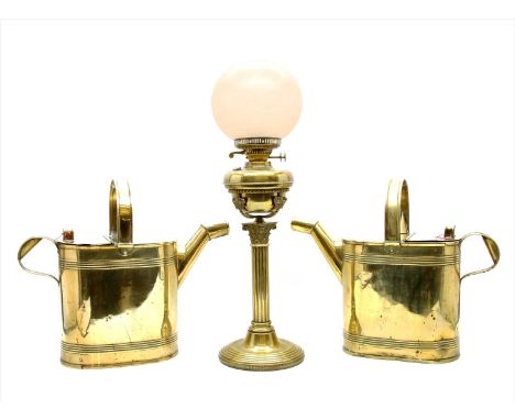 A pair of brass water cans, and a brass oil lamp, the reservoir mounted with crowns