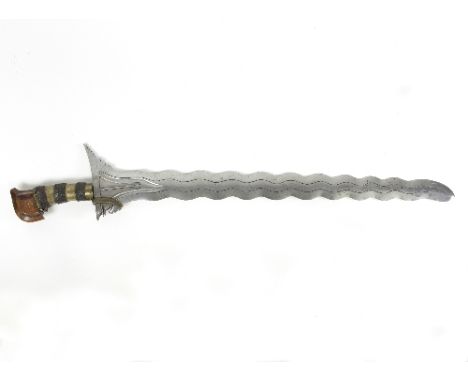 A kris dagger with serpentine steel blade and brass and metal plaited grip handle, 67cm long
