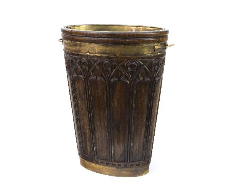 A carved oak and brass bound country house stick stand, of oval tapered form with Pugin style Gothic carving to the body, wit