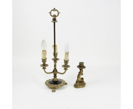 A gilt metal three-light table lamp, on circular base with three paw feet and a carved giltwood single candlestick