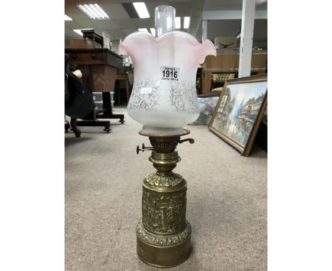 A brass embossed French oil lamp with shade and chimney