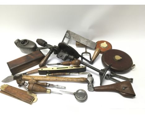 A collection of vintage tools to include a spirit level, tape measures etc and a vintage oil can.