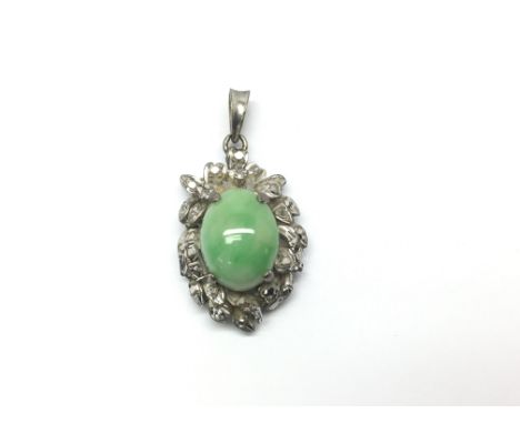 A pendant presenting a central oval piece of jade mounted on unmarked white metal.