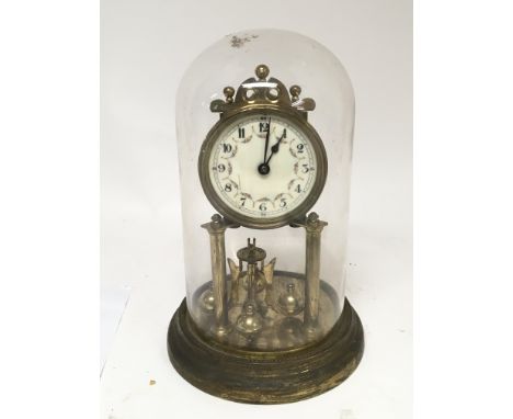A German brass two pillar clock under a glass dome with an enamel dial.