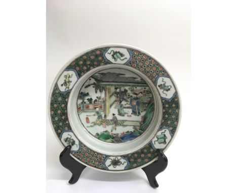 A fine, Chinese famille Vert large basin painted with with courtly figures in a garden, the rim decorated with scholar's obje