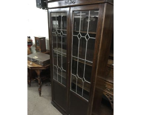 An oak bookcase with a pair of three Quarter lead light glazed doors.
