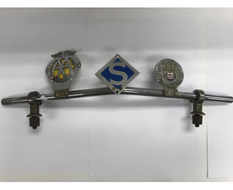 A vintage chrome badge bar with three badges including S owners club