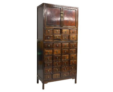 A Chinese hardwood apothecary cabinet 19th century, with two doors, opening to reveal a shelf, over a series of twenty four d