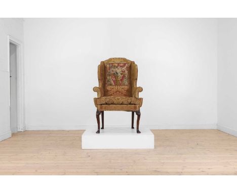 A George I walnut wingback armchair, early 18th century and later, the padded back and cushioned seat upholstered in silk dam