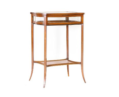 An Edwardian satinwood bijouterie table, c.1900, in the Sheraton taste with a hinged serpentine top inset with glass panels, 
