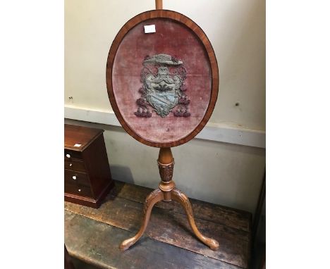 A 19th Century satinwood polescreen, oval panel containing a raised bullion work and tassel heraldic device, cabriole tripod 