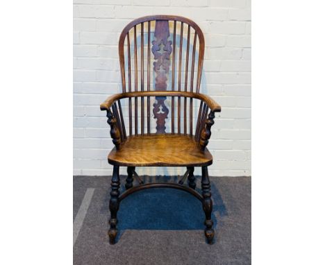 An early 19th century high backed Windsor elbow chair with a pierced and shaped central backsplat and a saddle seat, raised u