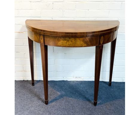 A Georgian mahogany fold over top demi lune card table with an inset baize lined playing surface, with tulipwood cross band a