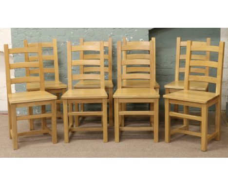 A set of eight modern light oak ladder back chairs.