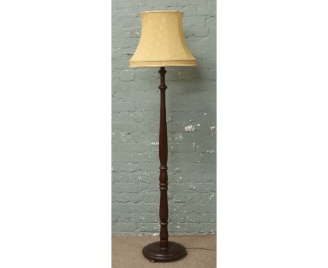 A turned mahogany standard lamp with gold coloured shade.