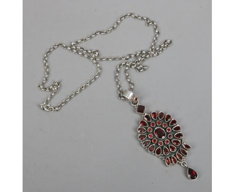 A large silver pendant on chain set with round and pear cut garnets.