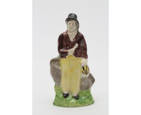 A CREAMWARE TOY FIGURE OF A SAILOR, c.1800, modelled wearing a black hat, brown jacket and yellow trousers, holding a long pi