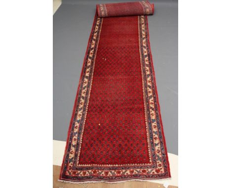 A PERSIAN STYLE WOOL RUNNER, late 20th century, the red field with repeating flower motif in blue within a pale blue and ivor