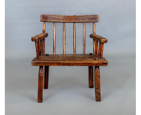 A PRIMITIVE ASH COMB BACK ARMCHAIR, 19th century, possibly Irish/Welsh, with curved top rail, splayed arms, wedge seat and sp