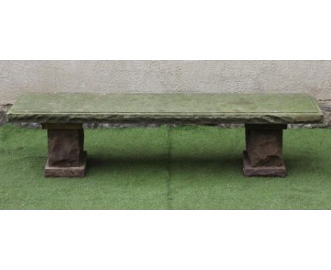 A SANDSTONE BENCH, the oblong panel seat with rough cut edge raised on a pair of similar stepped oblong supports, 71 1/4" x 1