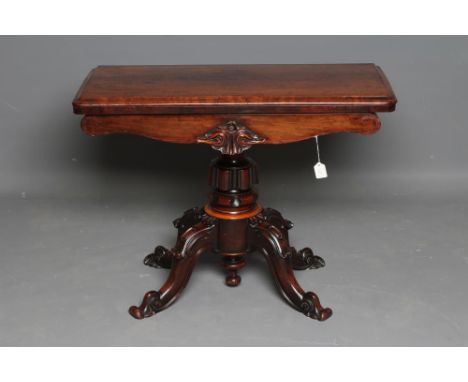 A VICTORIAN ROSEWOOD FOLDING CARD TABLE, the rounded oblong swivel top opening to a circular baize, waived frieze with carved