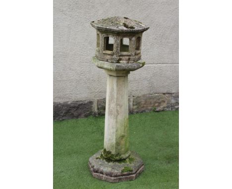 A COMPOSITION STONE BIRD FEEDER, of octagonal form, the Oriental style lantern top with arcaded sides, raised on faceted tape