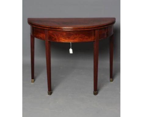 A GEORGIAN MAHOGANY FOLDING CARD TABLE, late 18th century, of demi lune form lined in red baize, moulded edged flame top over