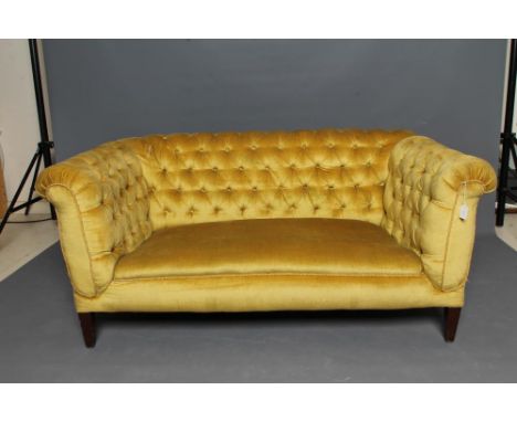 AN EDWARDIAN MAHOGANY FRAMED CHESTERFIELD SOFA with drop ends, button upholstered in yellow velvet, raised on square tapering