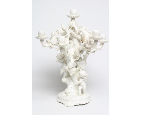 A LARGE VICTORIAN MOORE BROS. WHITE GLAZED CANDELABRUM, modelled as three cherubs climbing a fir tree, with six branches issu