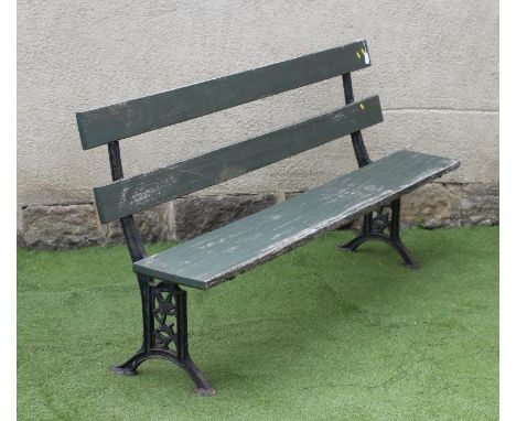 A VICTORIAN PARK BENCH, with open twin plank back, similar hinged seat, on square section end supports pierced with foliate s