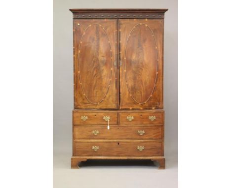 A GEORGIAN MAHOGANY LINEN PRESS, late 18th century, the moulded cornice over roundel studded frieze, two doors below each wit