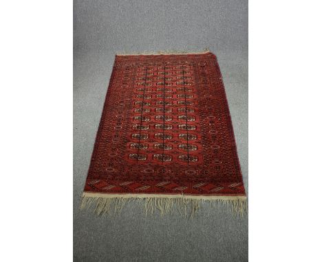 Carpet, Bokhara, gul motifs on burgundy field. L.215 W.140cm. 