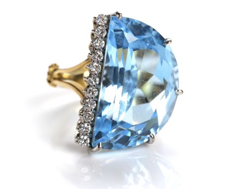 IMPRESSIVE TOPAZ AND DIAMOND RING
set with a large faceted D-shaped blue topaz, flanked by a row of eleven brilliant cut diam