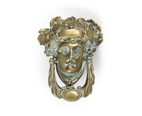 A GEORGIAN STYLE BRASS DOOR KNOCKER IN THE FORM OF A CLASSICAL FEMALE MASK,with leaf sing handle. 18cm high