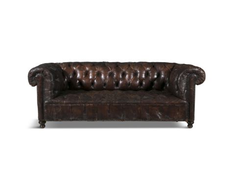 A BUTTONBACK BROWN LEATHER CHESTERFIELD SOFA of traditional design with out-scrolling arms and back, studded trim and short t