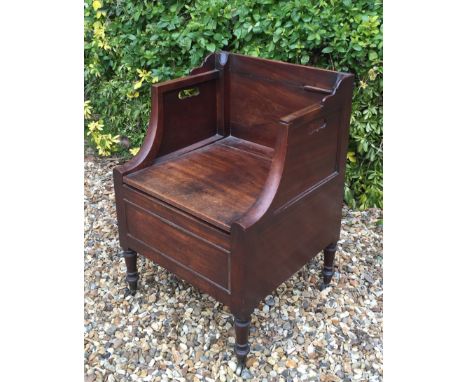 A GEORGIAN MAHOGANY COMMODE ARMCHAIR With turned legs and brass cup castors.