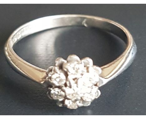 A VINTAGE 18CT WHITE GOLD AND DIAMOND CLUSTER RING Having seven round cut diamonds, held in a flower head style setting (size